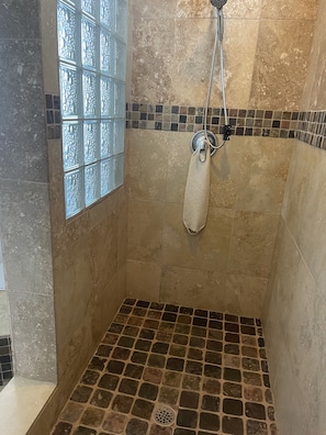 Een bad/douchecombinatie, een bubbelbad, een haardroger, handdoeken