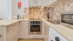 A modern kitchen with a built-in oven, a dishwasher, and a sink. - Garrett Terrace (Setúbal)