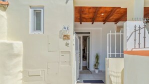 A building entrance with a wooden ceiling, a small window, and a door with a mailbox. - Garrett Terrace (Setúbal)