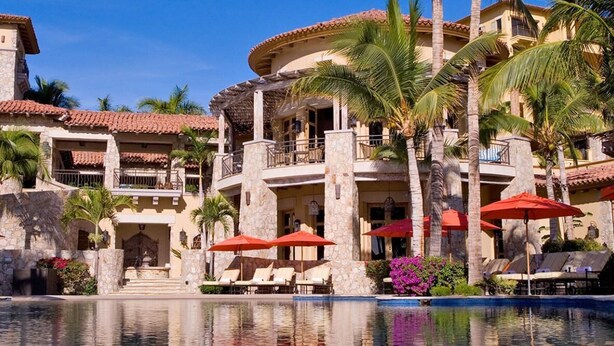 A resort with a pool, palm trees, and red umbrellas. - Spacious 4 bedroom 3.5 bath with a great view from building two second level. (Cabo San Lucas)