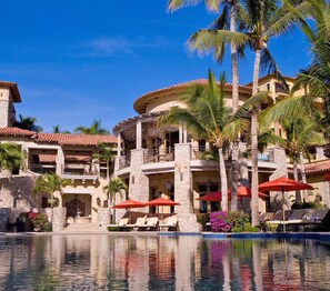 A resort with a pool, palm trees, and red umbrellas. - Spacious 4 bedroom 3.5 bath with a great view from building two second level. (Cabo San Lucas)