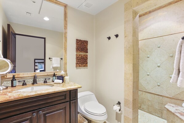 Un baño con tocador doble lavamanos, inodoro, un espejo grande y zona de ducha con puerta de cristal.