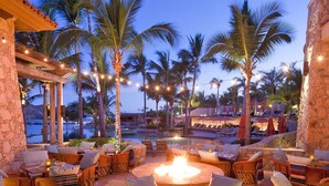 An outdoor seating area with wicker furniture, a fire pit, and string lights. - Spacious 4 bedroom 3.5 bath with a great view from building two second level. (Cabo San Lucas)