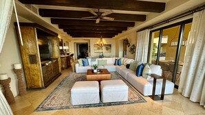 A spacious living room with a large sectional sofa, a coffee table, and a ceiling fan. - Spacious 4 bedroom 3.5 bath with a great view from building two second level. (Cabo San Lucas)