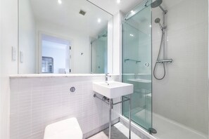 A modern bathroom with a glass-enclosed shower, a white sink, and a visible toilet. - Regent Style Soho Loft - Best of Both Worlds (London)