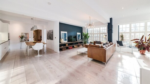 A spacious living area with a modern sofa, a dining table, and a kitchen in the background. - Regent Style Soho Loft - Best of Both Worlds (London)