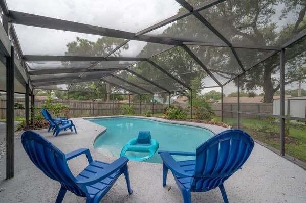 A covered outdoor swimming pool with blue chairs and a floating ring.