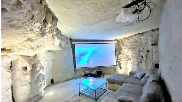 An ice cave interior with a television, seating, and a projector.