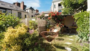 A garden with a chair, a table, and a potted plant.