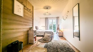 A cozy bedroom with a bed, a chair, a radiator, and a view of the garden.