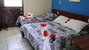 A hotel room with two beds, each with patterned bedding and red flowers. - Pousada Lusitana (Ipojuca)