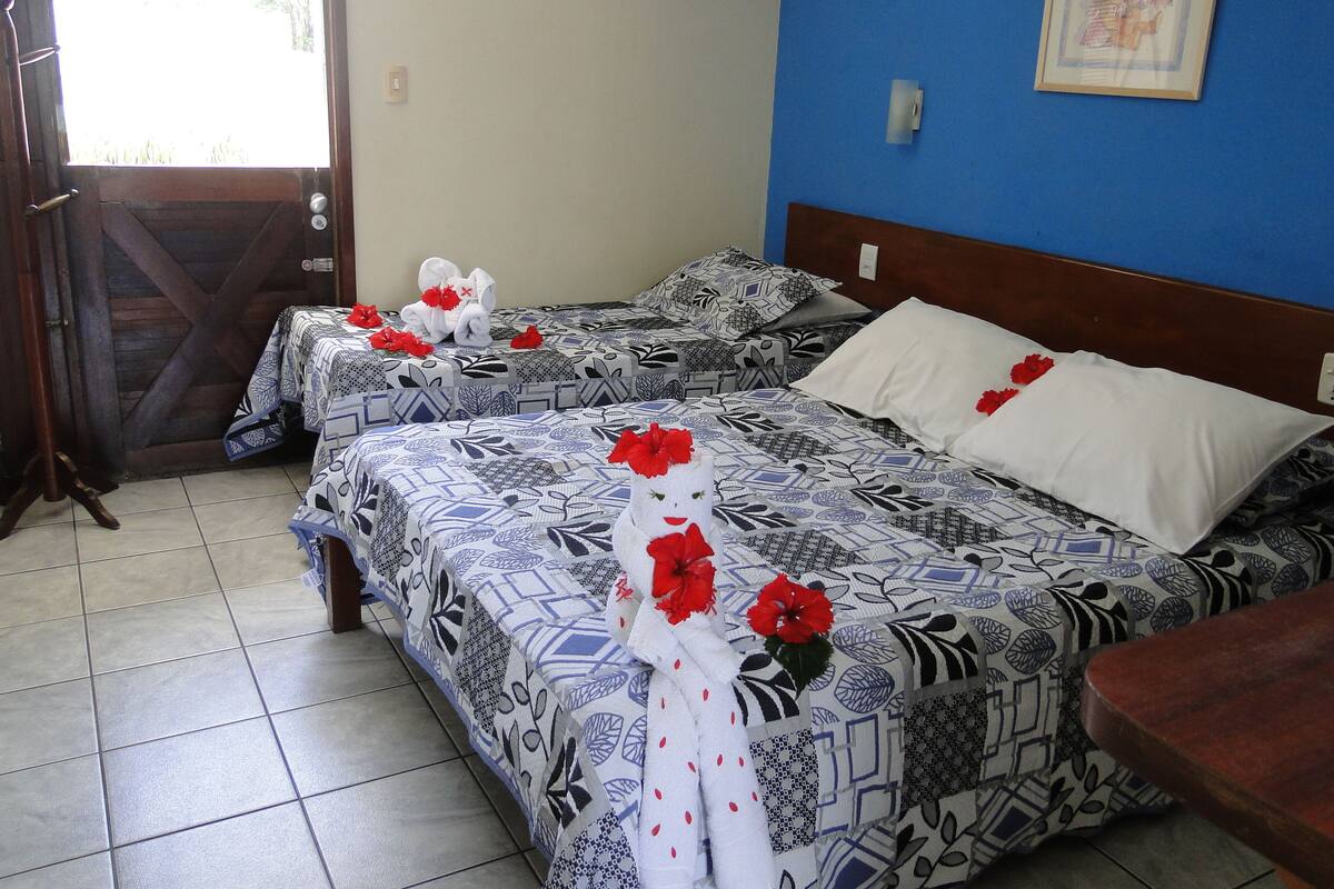 Habitación de hotel con dos camas, cada una con ropa de cama estampada y flores rojas.