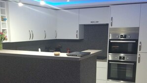 A modern kitchen with a central island, built-in appliances, and a sleek design. - Lovely 2-bed Apartment in Coventry (Coventry)