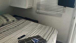 Ett hotellrum med en säng, en tv som är monterad på väggen och ett fönster med persienner.
