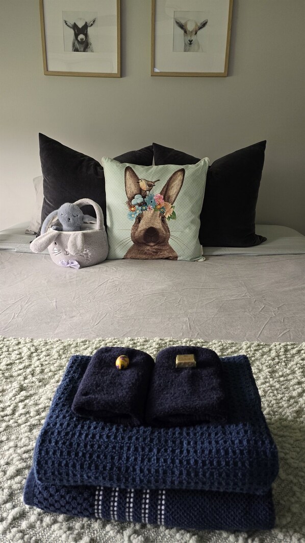 A bed with pillows, a stuffed toy, and a knitted item on a textured rug.