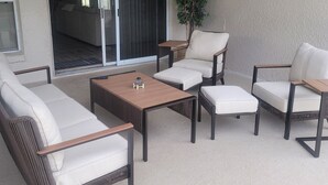 Un patio al aire libre con mobiliario de mimbre, un ventilador de techo y un televisor montado en la pared.