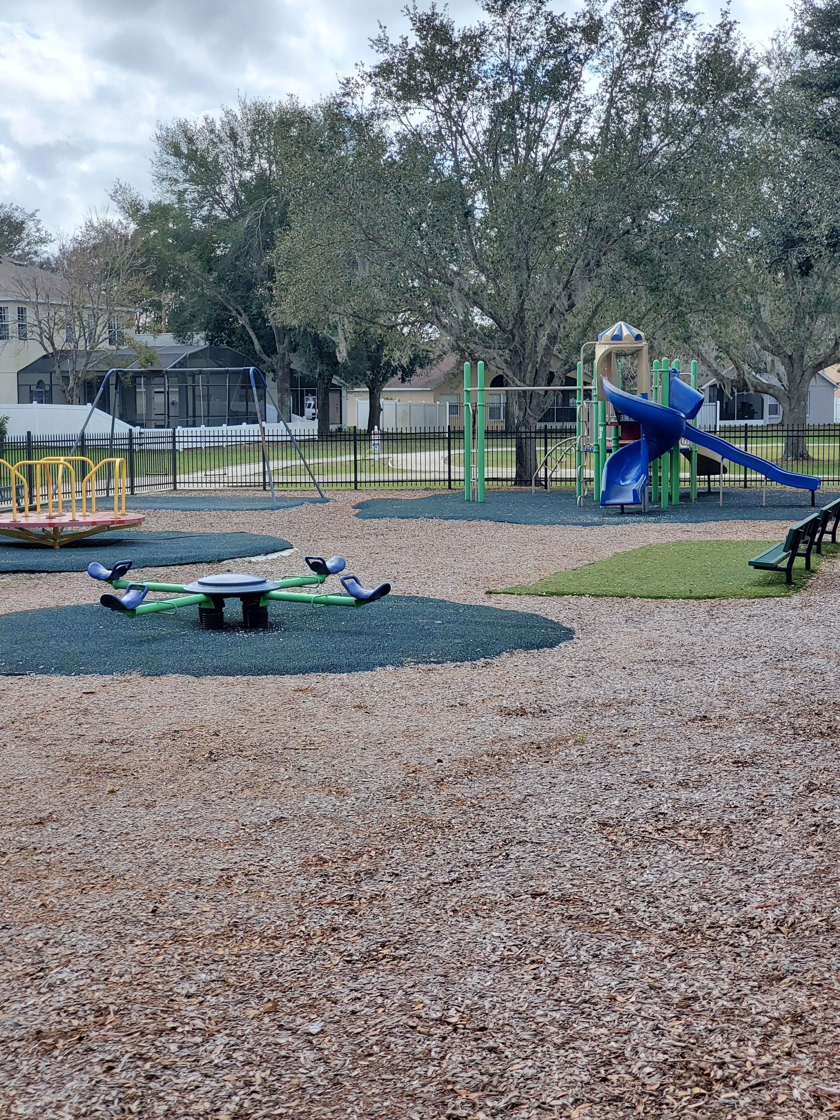 Un'area giochi con uno scivolo blu, altalene e una struttura per arrampicarsi.