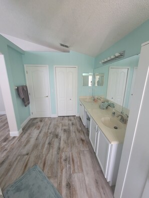 A spacious kitchen with a large island, white cabinets, and a light teal wall color. - A perfect place to watch the Sunset (Clermont)