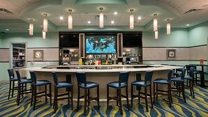 A bar area with a counter, multiple stools, and a large screen displaying an image. - 8BR Disney Getaway In Champions Gate! FREE POOL HEAT if you book by May 1st (Davenport)