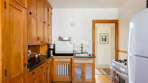A kitchen with wooden cabinets, a stove, and a refrigerator. - Classic Macalester Area St. Paul Duplex (Saint Paul)