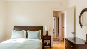 A bedroom with a bed, nightstand, dresser, and a mirror. - Classic Macalester Area St. Paul Duplex (Saint Paul)