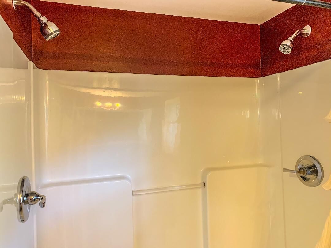 Ein Badezimmer mit einer weißen Badewanne, einer Dusche mit roter Akzentwand und einer Tür mit silbernem Griff.