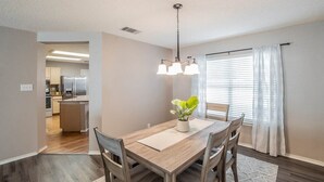A dining area with a wooden table, chairs, a hanging light fixture, and a potted plant. - Fresh, Clean & Comfortable Place in Round Rock (Round Rock)