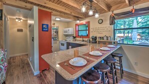 A kitchen with a granite island, bar stools, a microwave, and a view of the outdoors. - 'Casa Verde' Cabin w/ Fire Pit: 4 Mi to Ski (Cloudcroft)