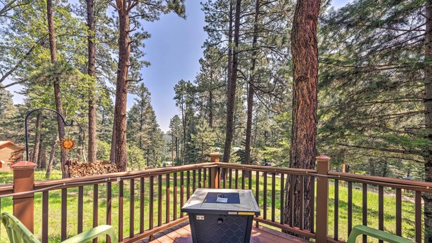 A deck with a trash can, two green chairs, and a wooden railing overlooking a forest. - 'Casa Verde' Cabin w/ Fire Pit: 4 Mi to Ski (Cloudcroft)