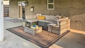 Ein überdachter Patio-Bereich mit einer Sofagarnitur, einem kleinen Tisch und einem Rattantisch.