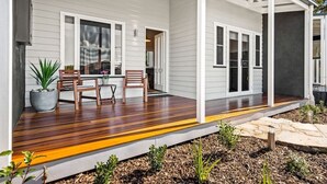 Une maison avec une terrasse en bois, un revêtement extérieur blanc et une véranda.
