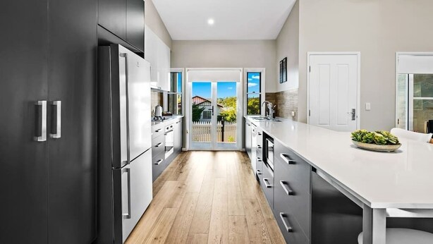 Une cuisine moderne avec des meubles de couleur sombre, des appareils  électroménagers en acier inoxydable et un grand îlot central.