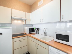 Een koelkast, een vaatwasser, kookgerei, borden en bestek