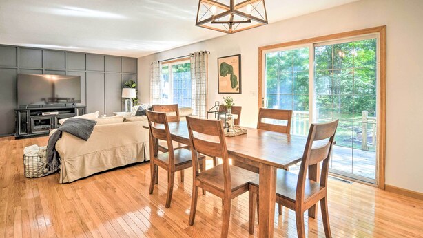 A modern living room with a sofa, TV, wooden dining table, and chairs. - Upscale Family Cottage < 1 Mi to Higgins Lake (Roscommon)