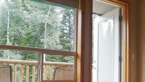 Een slaapkamer met een groot raam, een bed en een deur naar een balkon.