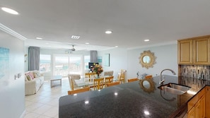 A modern kitchen with a central island, dining area with chairs, and a view of the outdoors.