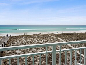 A beach view with a wooden deck and sandy dunes.