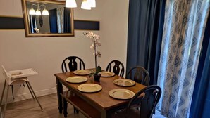 A dining area with a wooden table set for six, six chairs, a small potted plant, and a mirror on the wall. - Near Universal and other Orlando Attractions (Orlando)