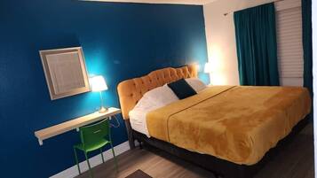 A bedroom with a bed, a desk, and a chair.