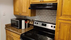 A kitchen with wooden cabinets, a microwave, a stove, and a tiled backsplash. - Near Universal and other Orlando Attractions (Orlando)
