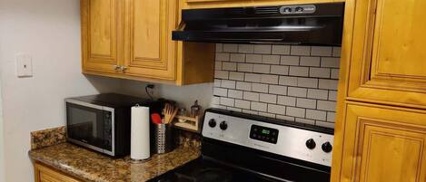 A kitchen with wooden cabinets, a microwave, a stove, and a tiled backsplash.