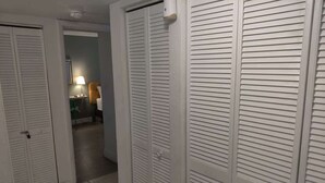 A hallway with white louvered closets, a lamp, and a chair. - Near Universal and other Orlando Attractions (Orlando)