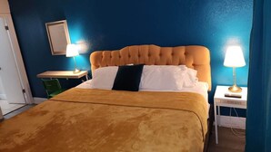 A hotel room with a bed, two bedside tables with lamps, a chair, and a door. - Near Universal and other Orlando Attractions (Orlando)