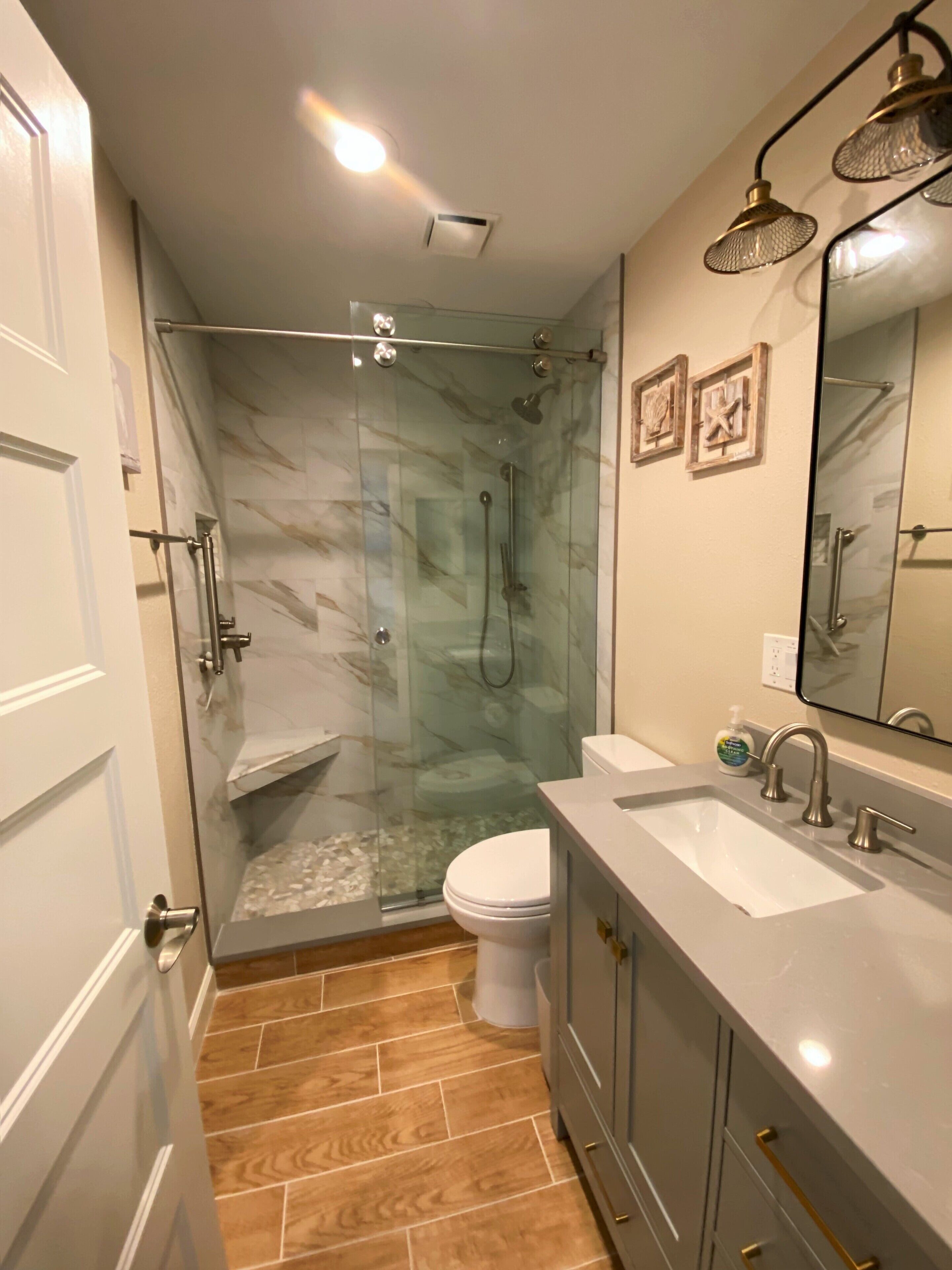 A bathroom with a glass-enclosed shower, a toilet, a sink, and a vanity with a mirror.