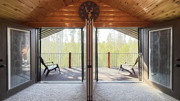 Une pièce avec un plafond en bois, une grande horloge et un balcon équipé de deux chaises.