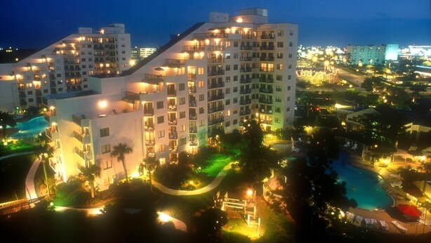A multi-story hotel with balconies, a swimming pool, and landscaped areas.