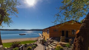 A wooden cabin with a stone staircase leading to a dock by a lake.