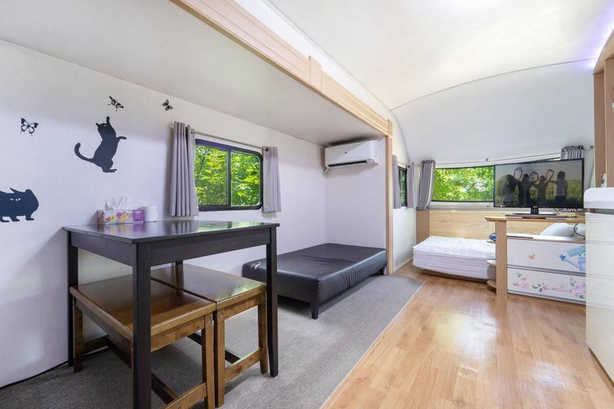 Una habitación pequeña con cama, una mesita, un escritorio y televisión.