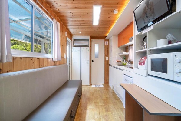 Un pasillo estrecho con paredes y piso de madera, que conduce a una puerta.