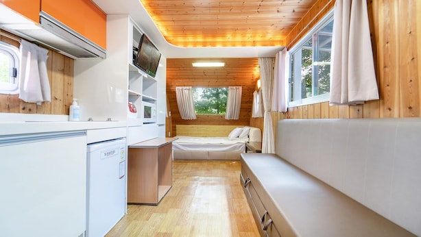 Interior compacto de una caravana con kitchenette, una cama y un baño pequeño.